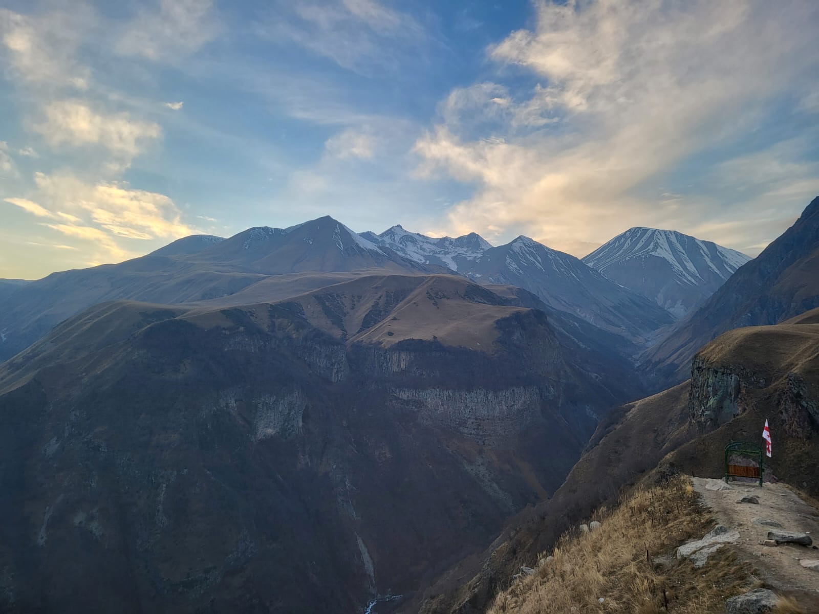 Snow-capped peaks of the Caucasus mountains in Georgia at dawn, seen across a deep valley